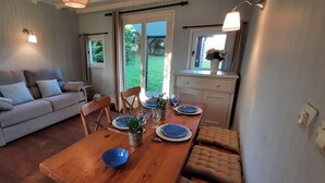 A cozy living room with a sofa, a dining table set for two, and a kitchen area with a window. - Le Clos Saint Martin, charming gîte - 14 pers- Chic countryside 35mn from the sea (Cavron Saint Martin)