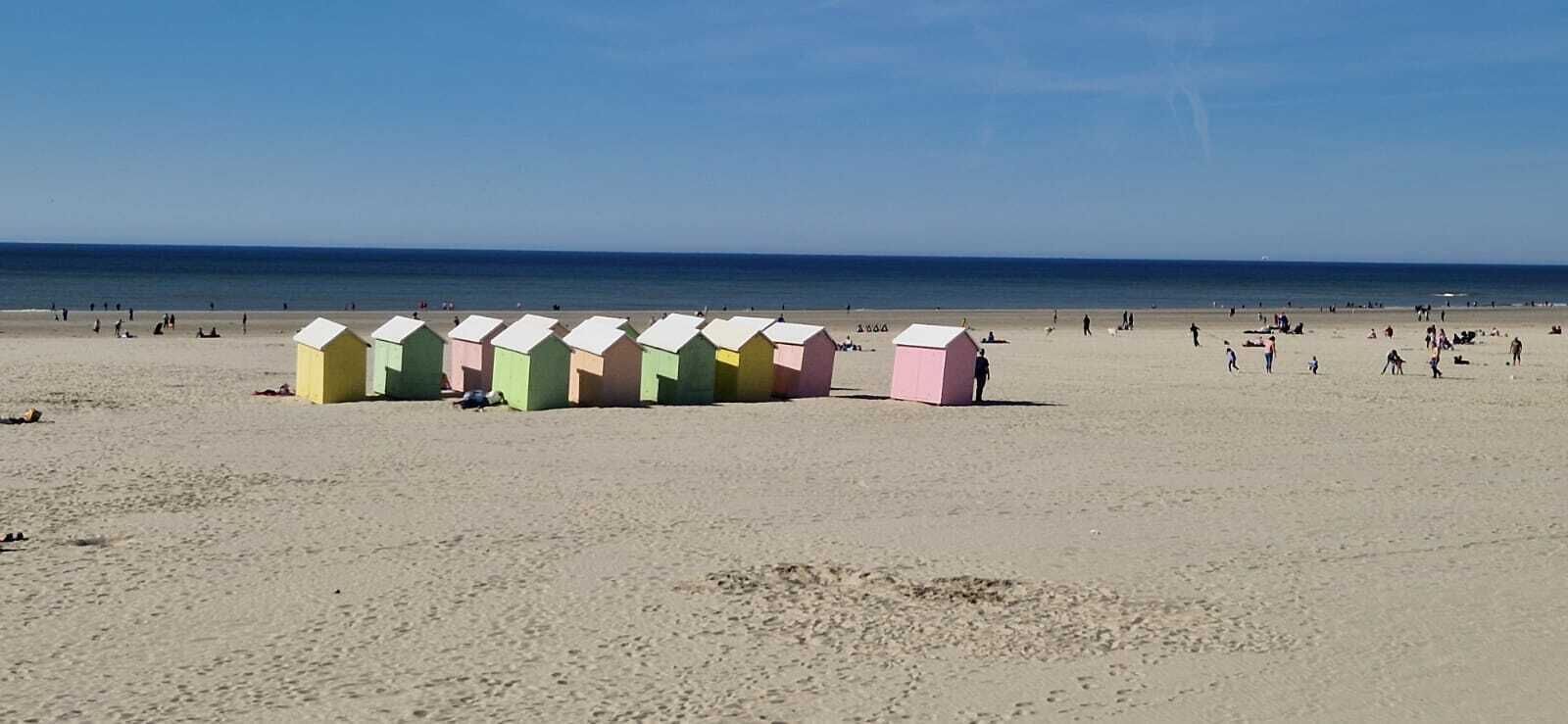 A beach with colorful beach huts and people in the distance.
