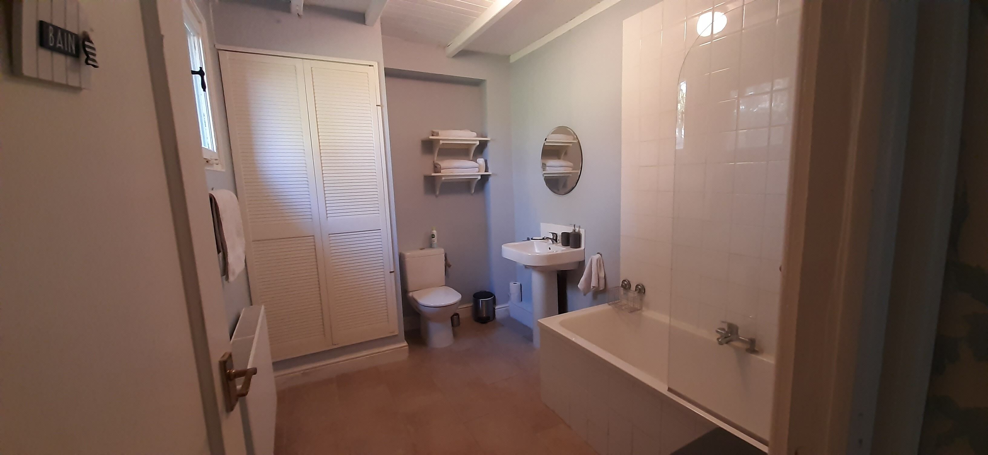 A bathroom with a toilet, sink, and bathtub. There is a towel rack and a mirror on the wall.