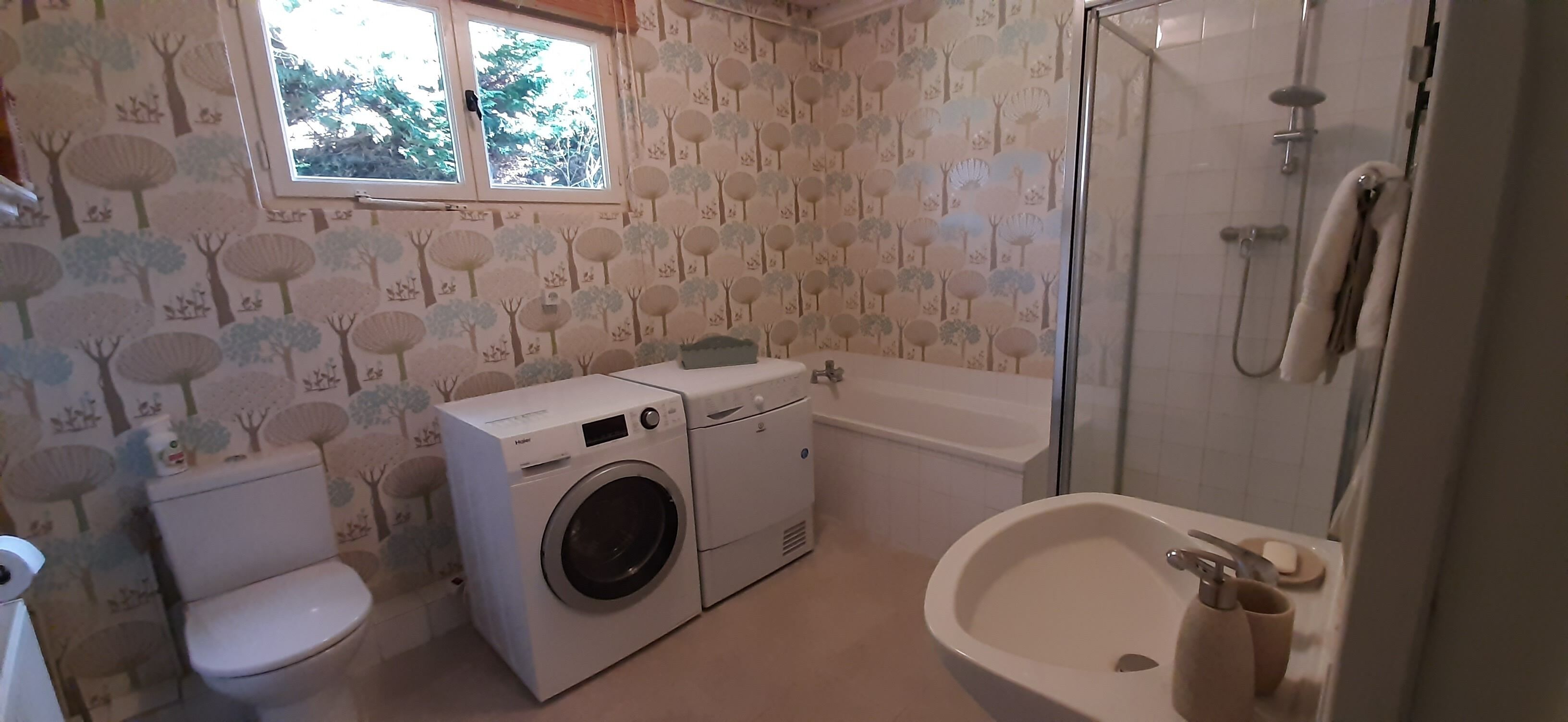 A bathroom with a washing machine, toilet, bathtub, and sink.