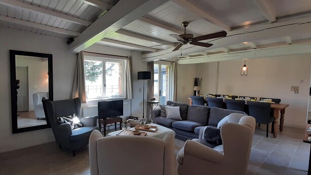 A spacious living room with a fireplace, a ceiling fan, and a dining area with a table set for two. - Le Clos Saint Martin, charming gîte - 14 pers- Chic countryside 35mn from the sea (Cavron Saint Martin)