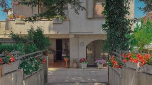 A courtyard with potted plants, a wooden fence, and a building entrance. - Cozy Home with Garden and Privacy (Spello)