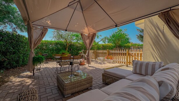 An outdoor patio with a covered seating area, wicker furniture, and a wooden fence in the background. - Cozy Home with Garden and Privacy (Spello)