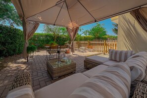 An outdoor patio with a covered seating area, wicker furniture, and a wooden fence in the background. - Cozy Home with Garden and Privacy (Spello)