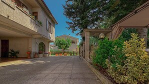 A courtyard with a paved walkway, potted plants, and a building with a balcony. - Cozy Home with Garden and Privacy (Spello)