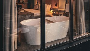 A modern bathroom with a large bathtub, a shower area, and a vanity with a mirror.