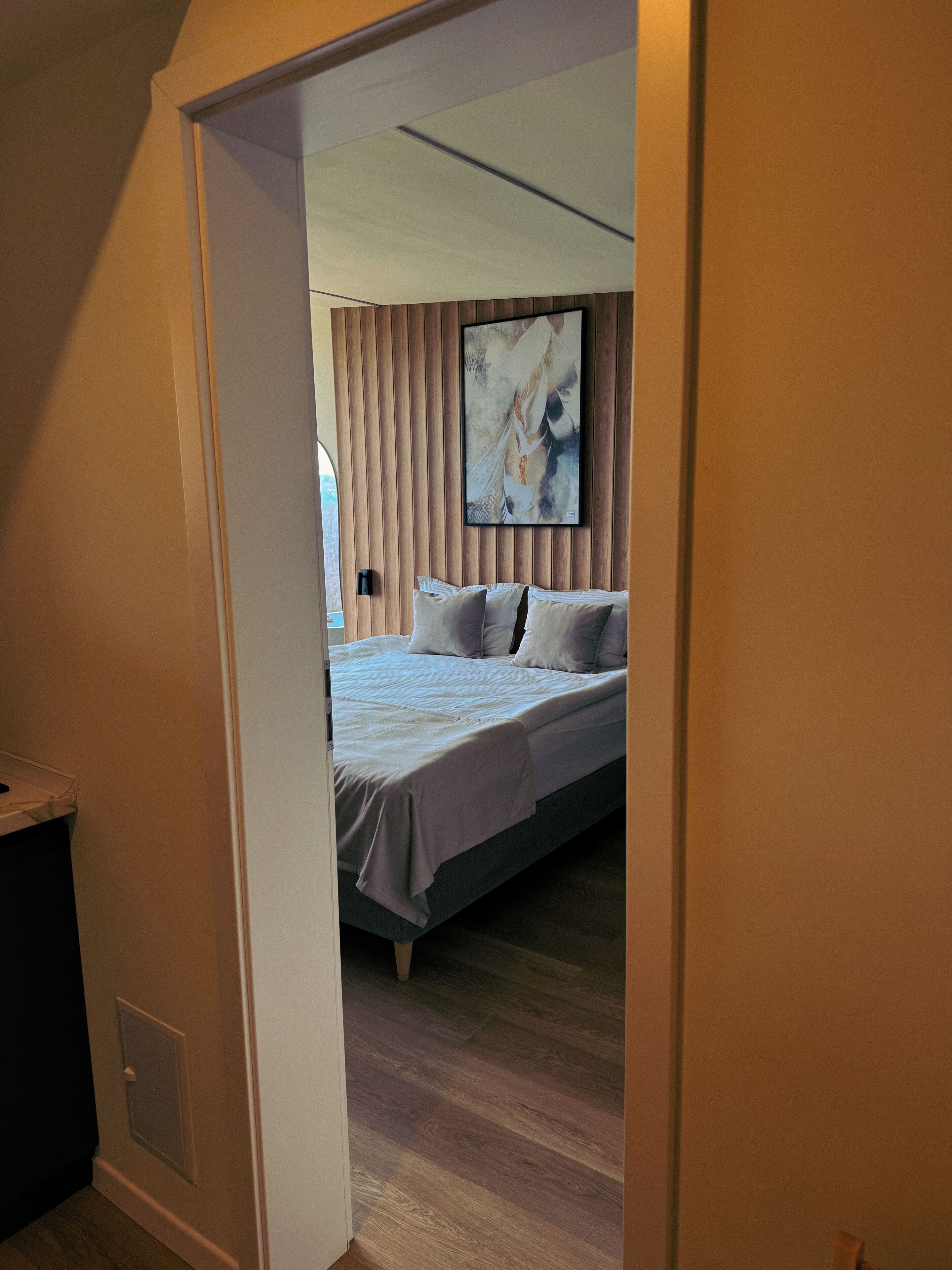 Un dormitorio con cama, una obra de arte en la pared y suelo de madera.