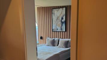 Un dormitorio con cama, una obra de arte en la pared y suelo de madera.