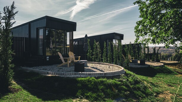 A modern outdoor living area with a circular seating arrangement, a wooden chair, and a fire pit.
