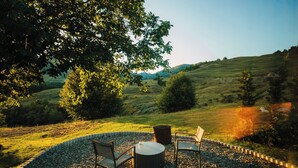 An outdoor seating area with a table and chairs, surrounded by a gravel path and a hedge.