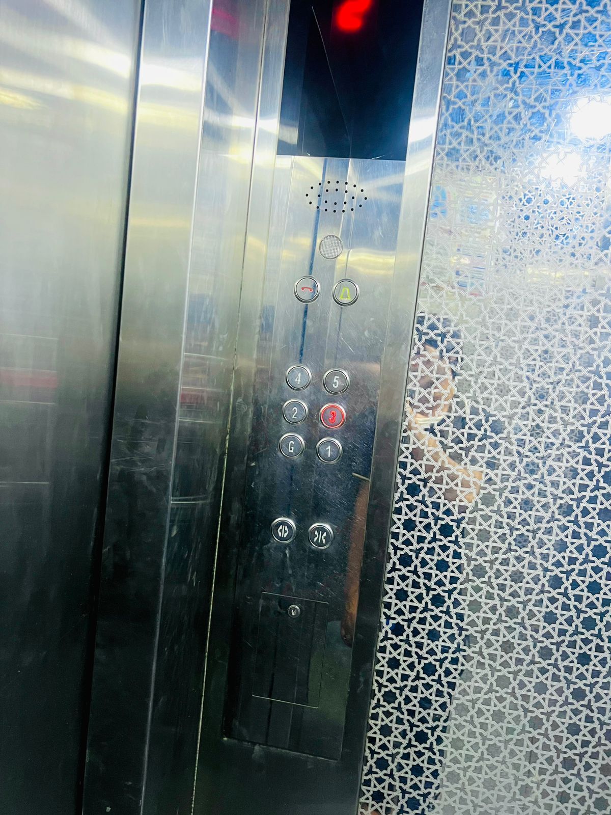 Panel de control de ascensor con botones numerados del 1 al 6, un botón de llamada y un sensor de puerta.