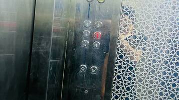 Panel de control de ascensor con botones numerados del 1 al 6, un botón de llamada y un sensor de puerta.