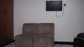 A room with a sofa, a television mounted on the wall, and a door.