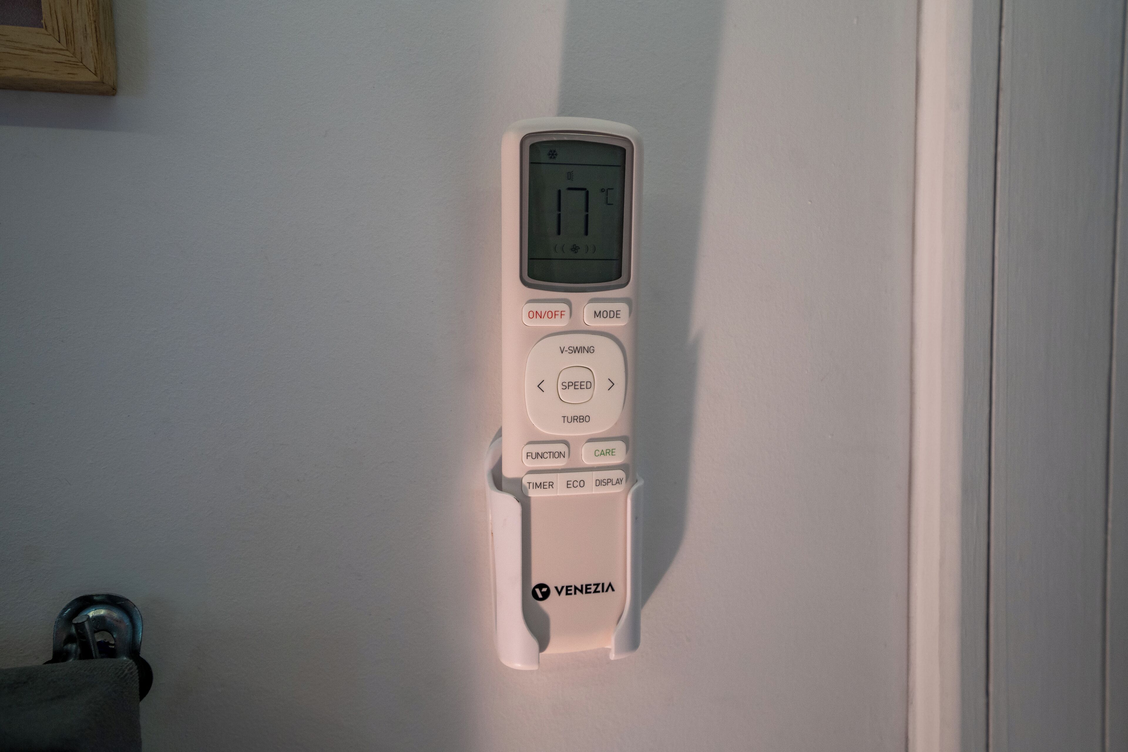 A white thermostat mounted on a wall with a digital display showing 17°C.