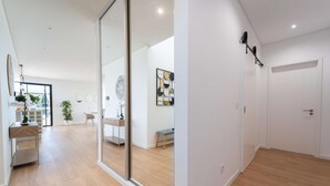 A modern interior with a wooden floor, a sliding glass door, a desk with a chair, and a bench.