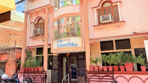 En rosa byggnad med en skylt som visar texten ”Hotel Krishnam Palace”.