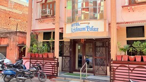 En rosa byggnad med en skylt som visar texten ”Krishnam Palace Hotel”.