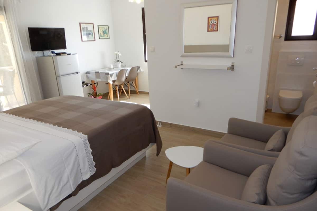Ein Hotelzimmer mit Bett, Sofa, kleinem Tisch, Fernseher, Schreibtisch und Bad.