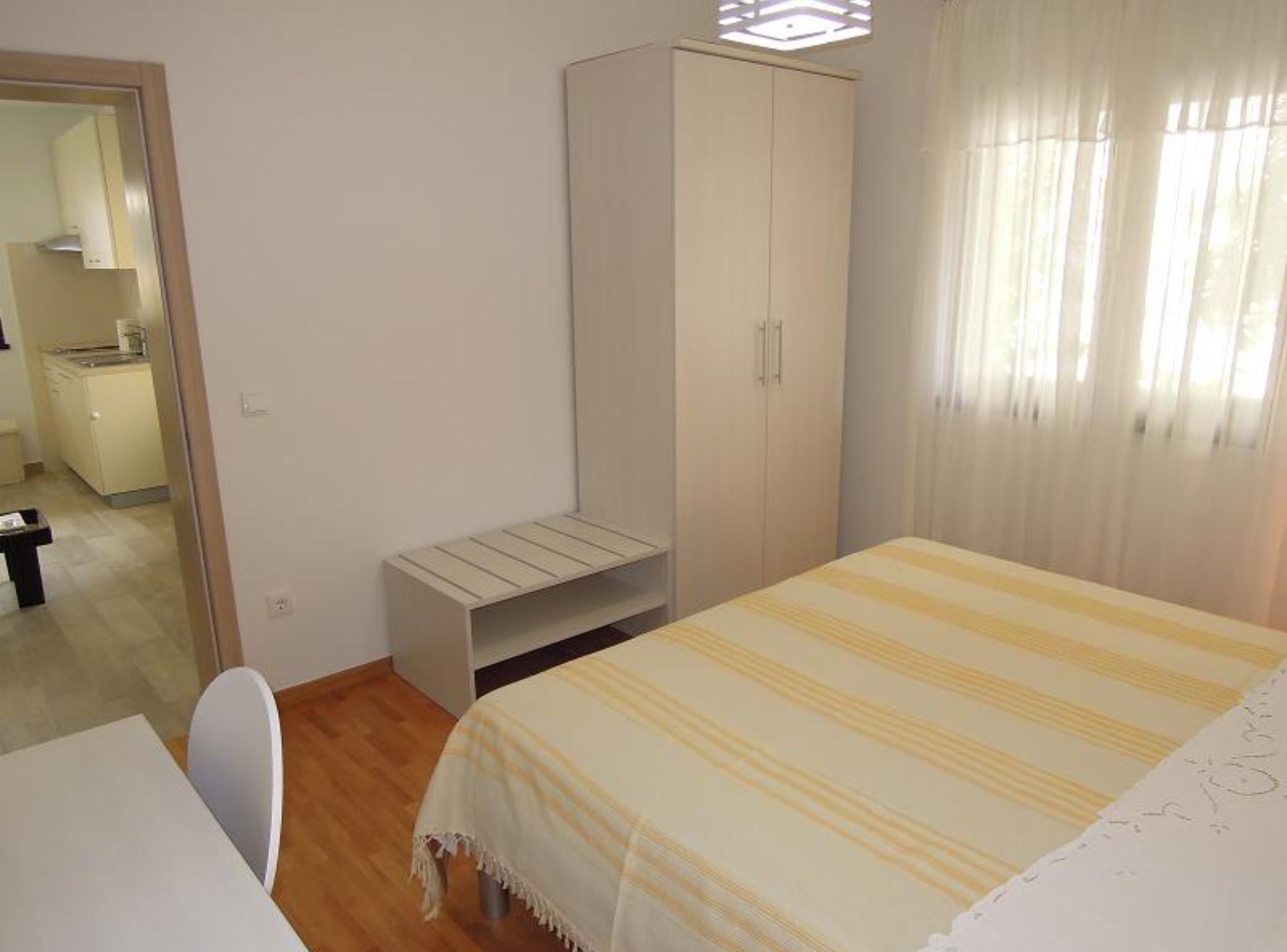 A bedroom with a bed, a wardrobe, a desk, and a chair.