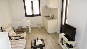 A compact living space with a sofa, a small dining table, a kitchen area, and a TV on a stand. - Cozy Retreat By The Sea Puntamika (Zadar)
