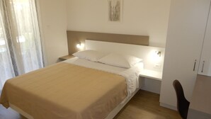 A neatly made bed with a beige bedspread, a white pillow, and a headboard with wall-mounted lights. - Cozy Retreat By The Sea Puntamika (Zadar)