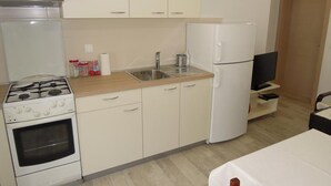 A compact kitchen with a stove, oven, sink, and refrigerator. - Cozy Retreat By The Sea Puntamika (Zadar)