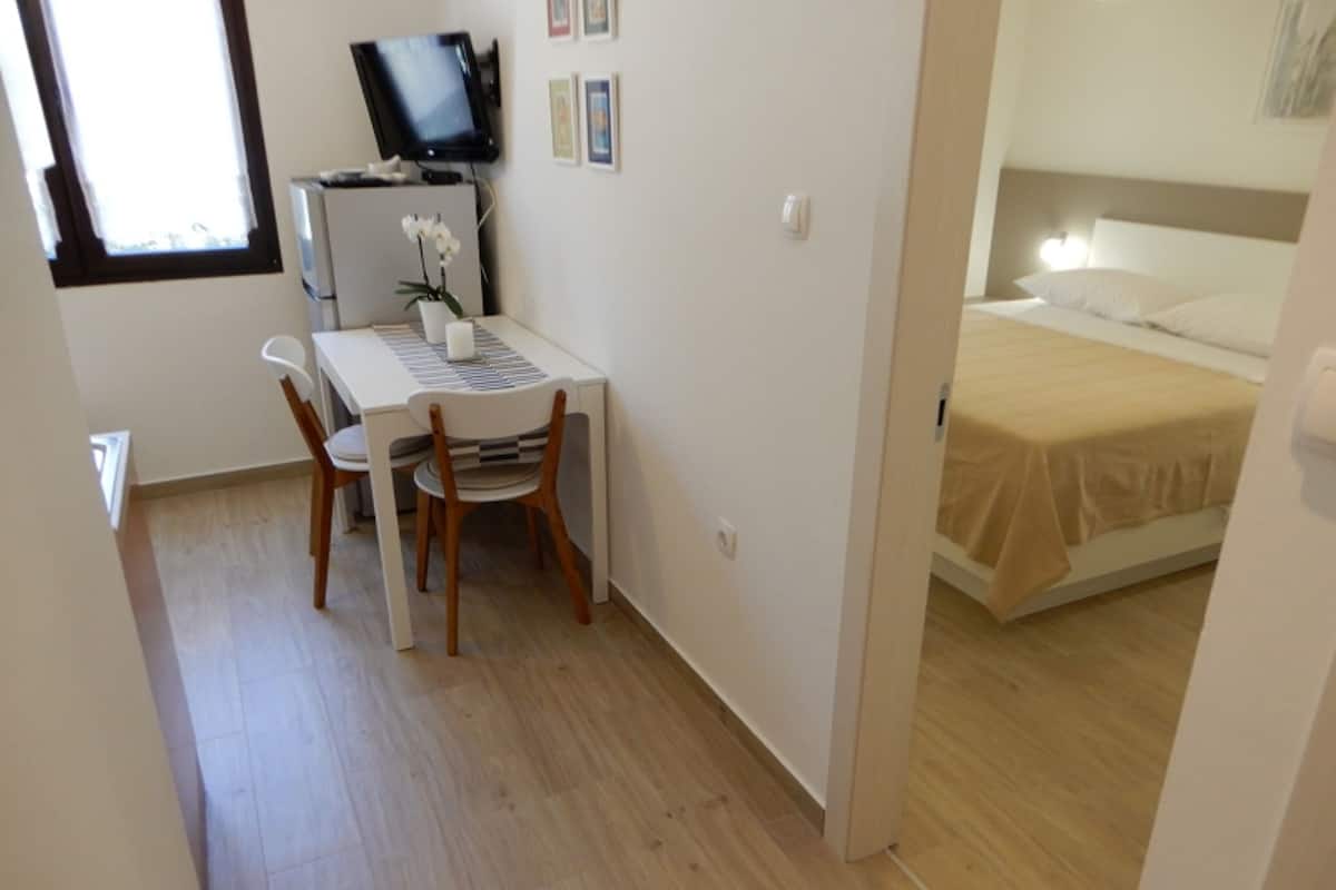 Ein kleines Zimmer mit Schreibtisch, Stuhl und Bett.
