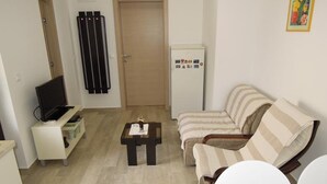 A living room with a sofa, a coffee table, a TV, and a refrigerator. - Cozy Retreat By The Sea Puntamika (Zadar)