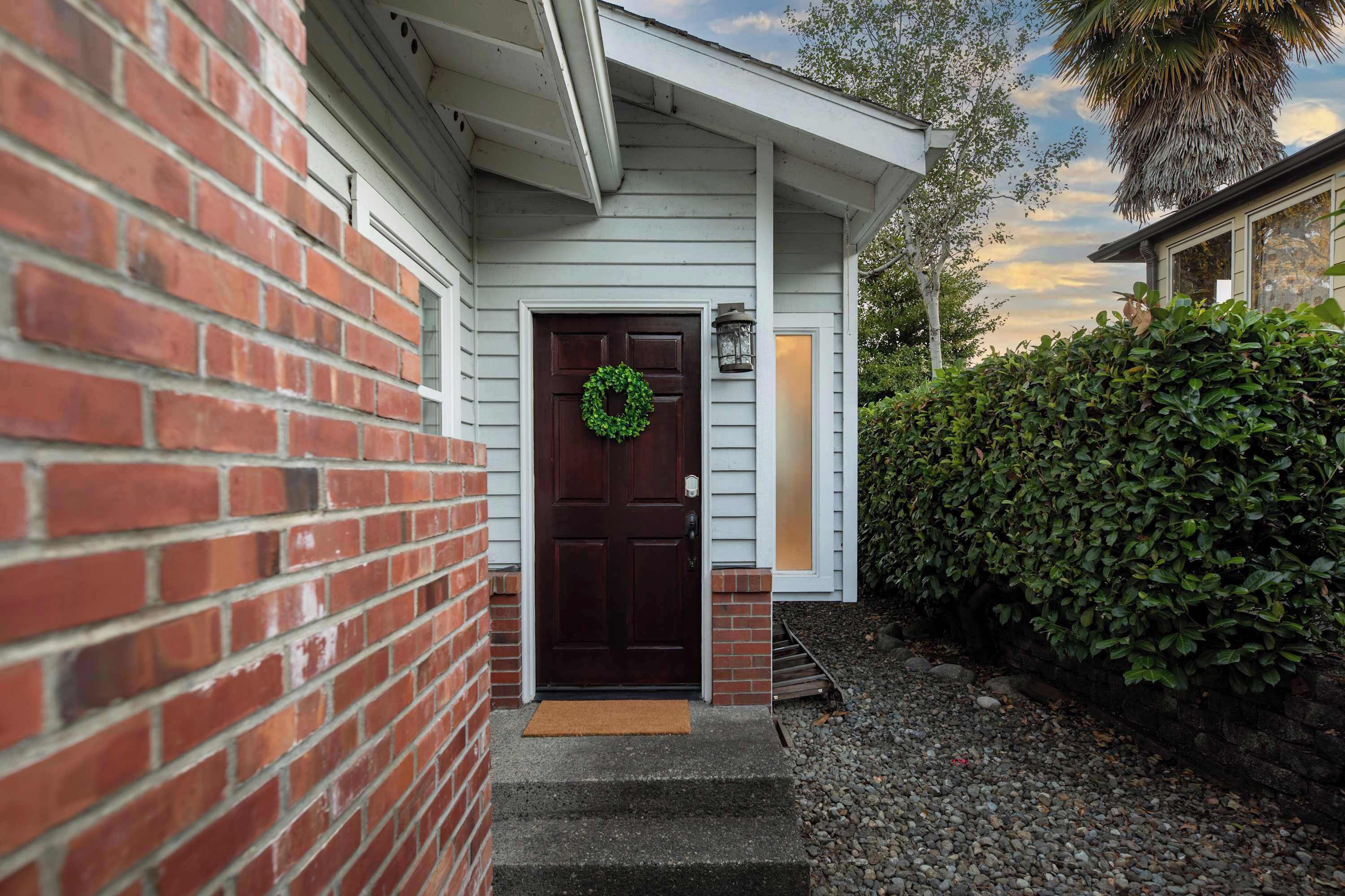 A house with a brick exterior, a dark wooden door with a green wreath, and a small porch area.