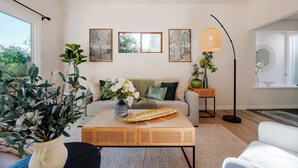 A living room with a sofa, coffee table, and potted plants. There are framed pictures on the wall and a floor lamp. - @ Marbella Lane - Nature Escape at Shady Lake (Renton)
