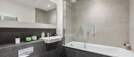 A modern bathroom with a glass-enclosed shower, a freestanding bathtub, and a vanity with a sink and mirror.