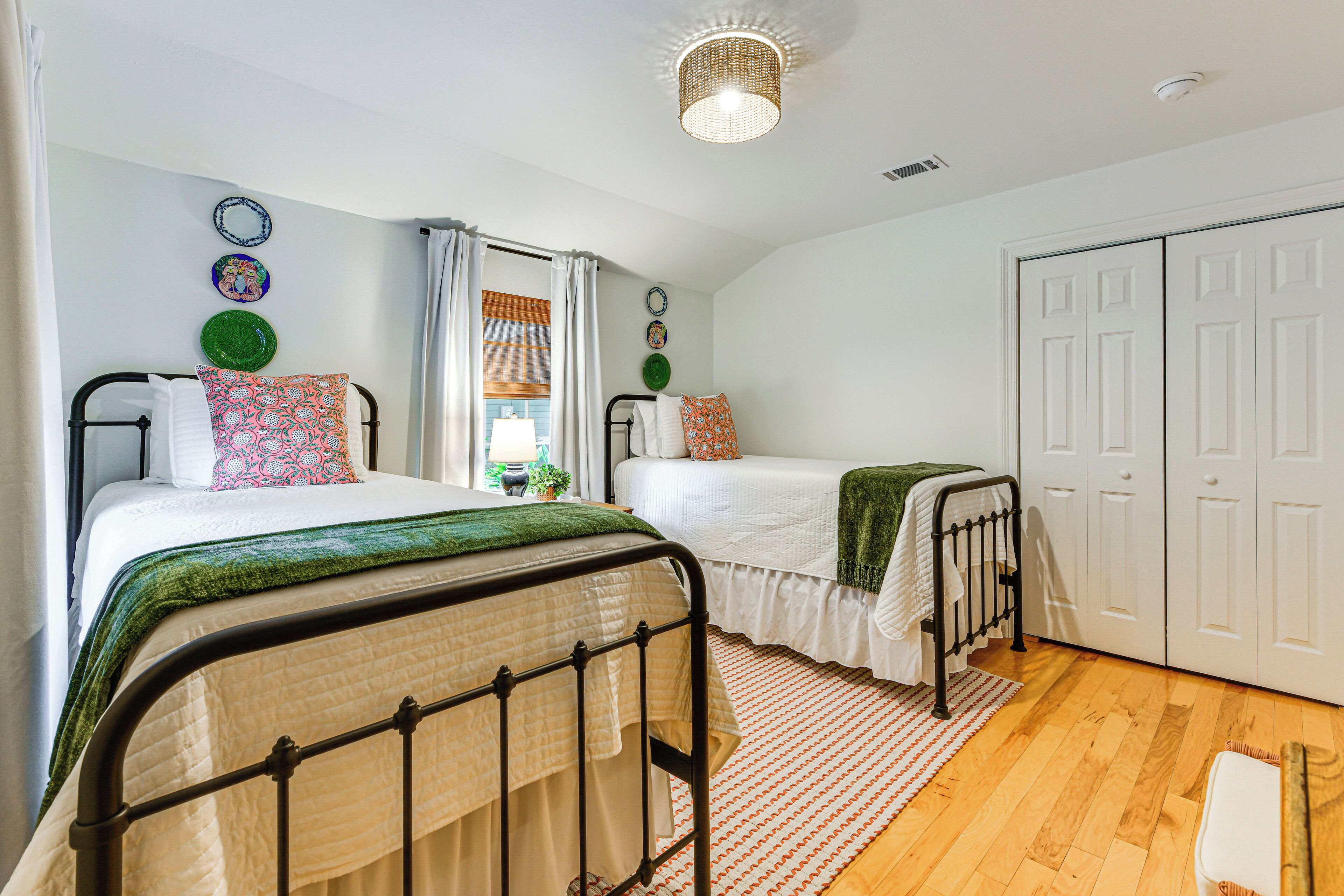 A bedroom with two beds, a wardrobe, and a window with curtains.