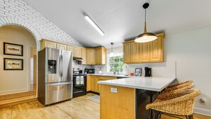 Een moderne keuken met houten kastjes, roestvrijstalen apparatuur en een groot kookeiland met barstoelen.