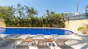Una piscina con lettini e palme.