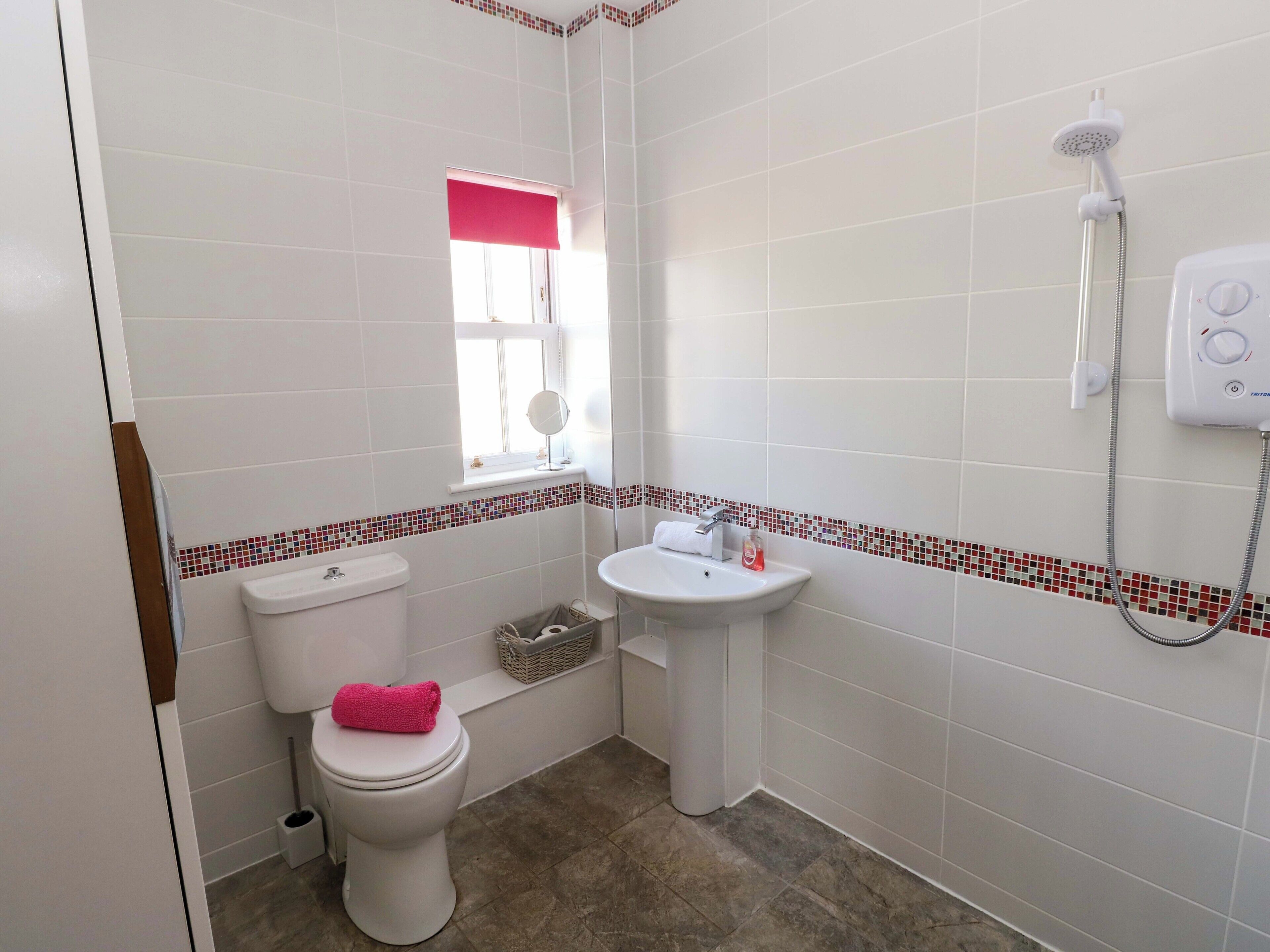 A small bathroom with a toilet, sink, and shower.