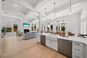 A spacious kitchen with a central island, white cabinetry, and pendant lighting.
