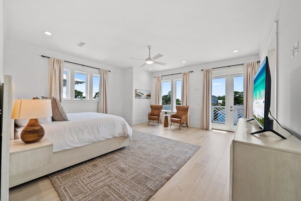 A bedroom with a bed, bedside table, lamp, and a TV on a stand.