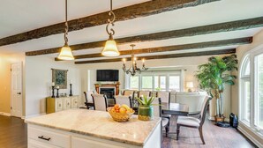 Una cocina espaciosa con una isla grande, vigas de madera y un comedor con candelabro.