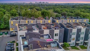 Ein moderner Apartmentkomplex mit mehreren Gebäuden, Außenbereichen zum Sitzen und einem sichtbaren Feuerbereich.