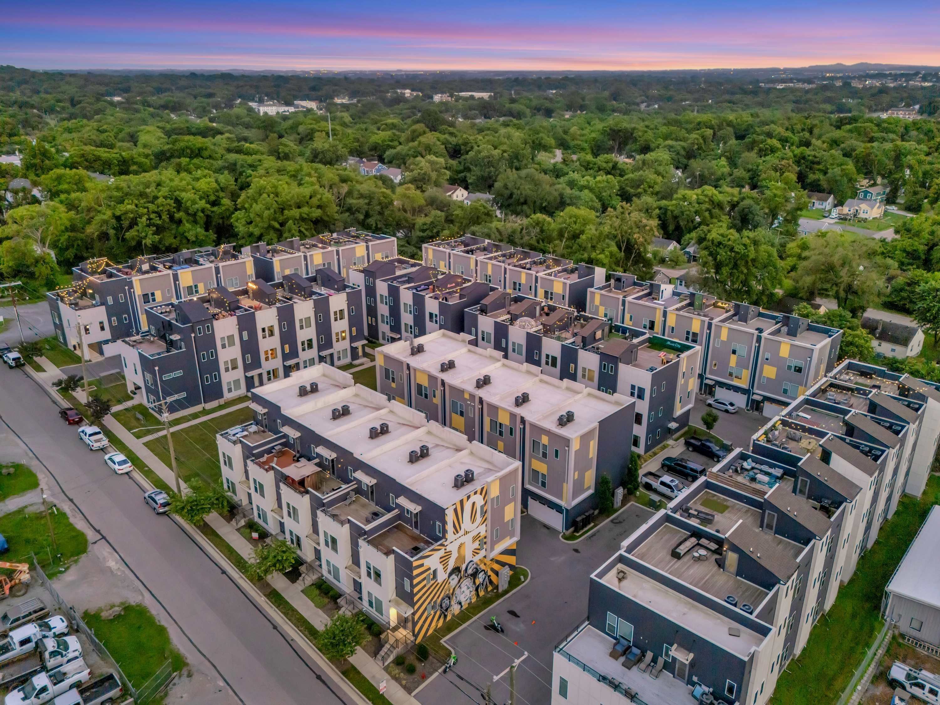 Un moderno complejo de apartamentos con varios edificios, un patio central y vistas a zonas verdes.