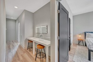A modern bedroom with a bed, bedside lamp, and a vanity with a mirror and lights. - Rooftop Deck Grill Ping Pong Near Downtown Nashville (Nashville)