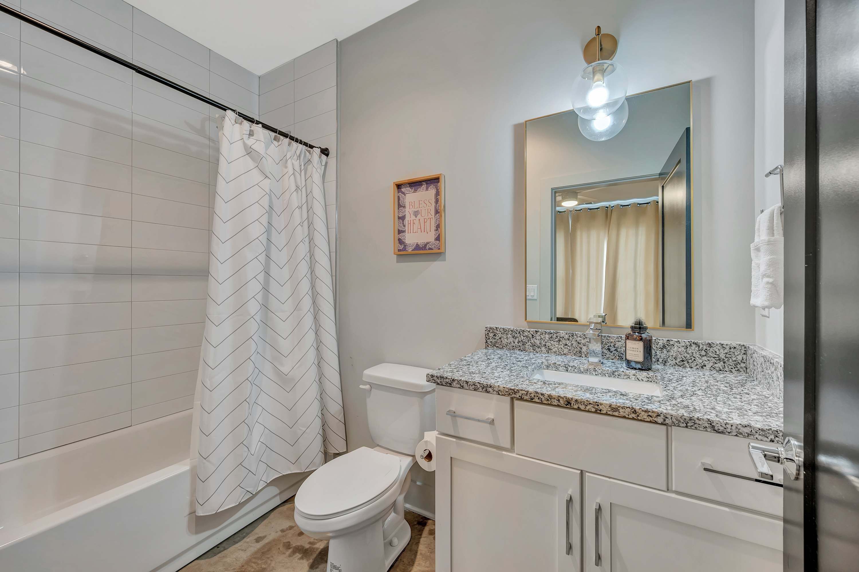 Un baño moderno con cortina de ducha, inodoro, lavabo y armario.