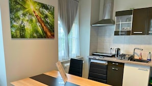 A modern kitchen with a dining area, featuring a wooden table, black chairs, a stove, and a sink. - Apartment in Trier,mosl - Mosel (Pellingen)