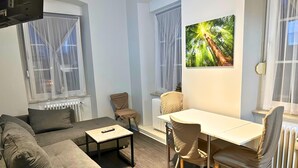 A modern living room with a sofa, a dining table with chairs, a radiator, and a painting on the wall. - Apartment in Trier,mosl - Mosel (Pellingen)