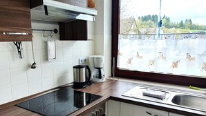 A kitchen with a stove, coffee maker, and a window with a view of a parking lot. - Apartment in Winterberg Near Ski Lift (Winterberg)