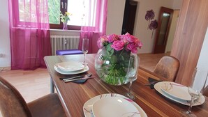 A dining table set with plates, cutlery, and a vase of flowers. - Apartment in Winterberg Near Ski Lift (Winterberg)