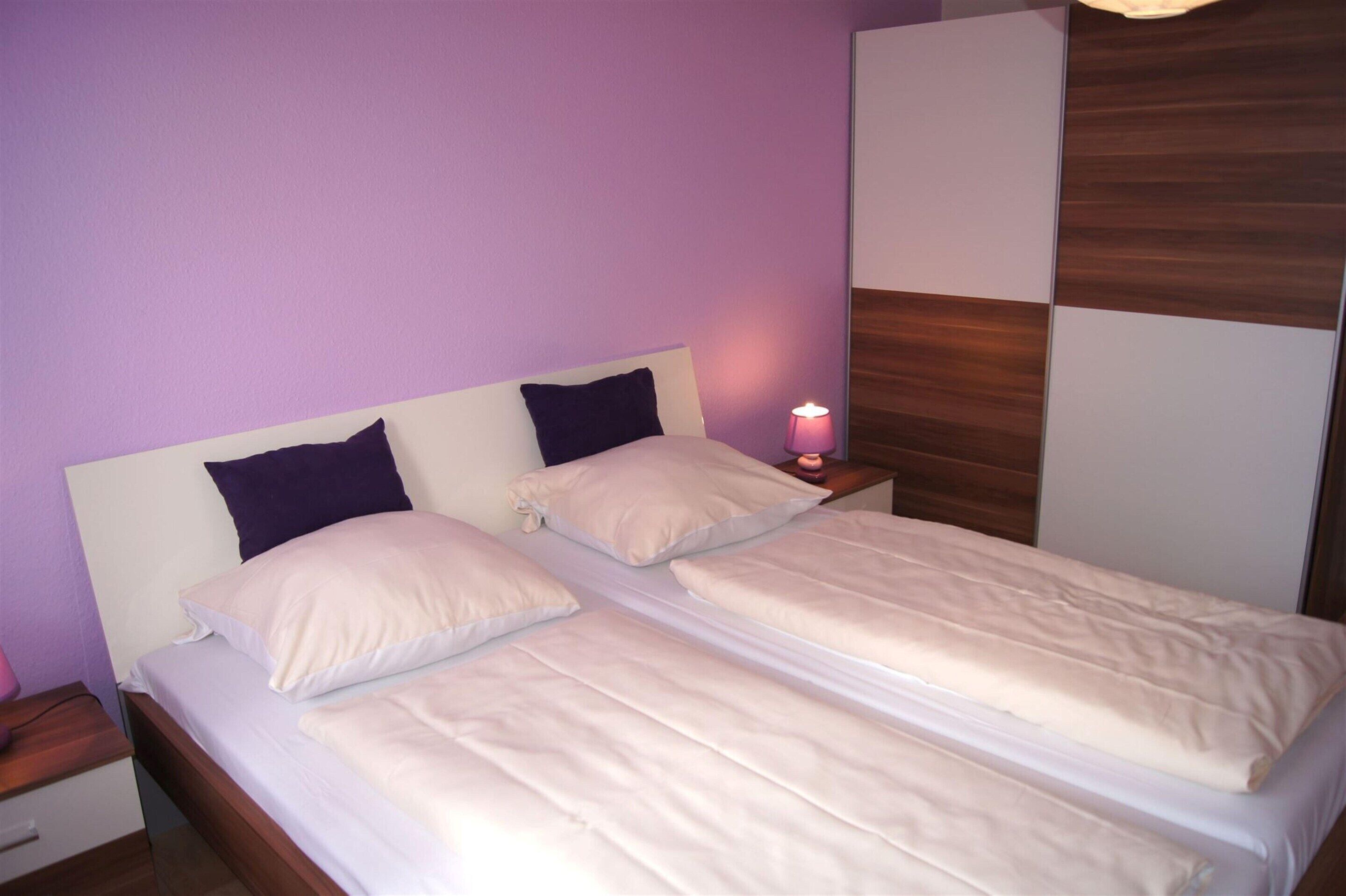 A double bed with two pillows, a bedside table with a lamp, and a wooden panel wall.