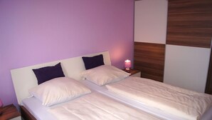 A double bed with two pillows, a bedside table with a lamp, and a wooden panel wall. - Apartment in Winterberg Near Ski Lift (Winterberg)