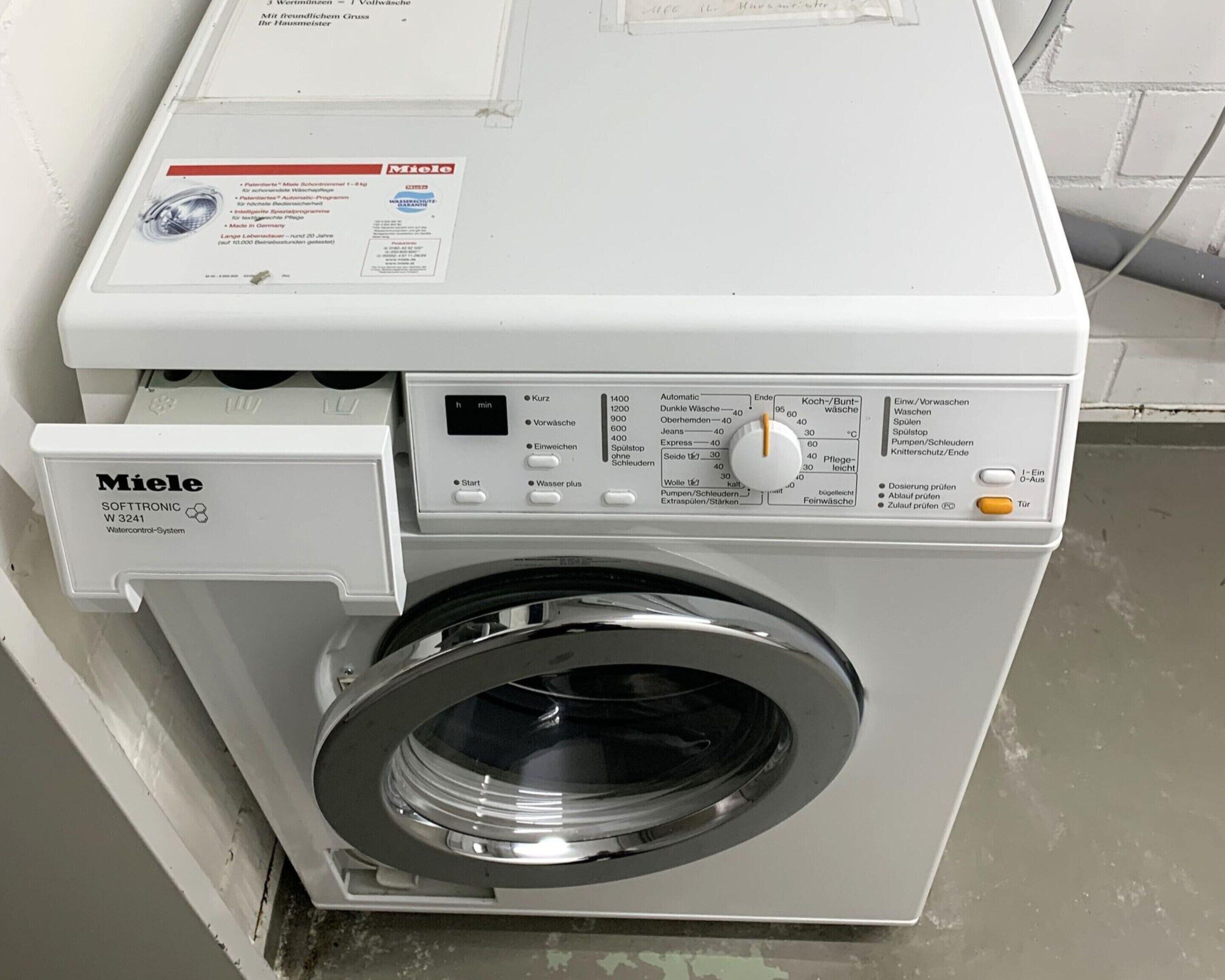 A white Miele washing machine with a control panel and a label.