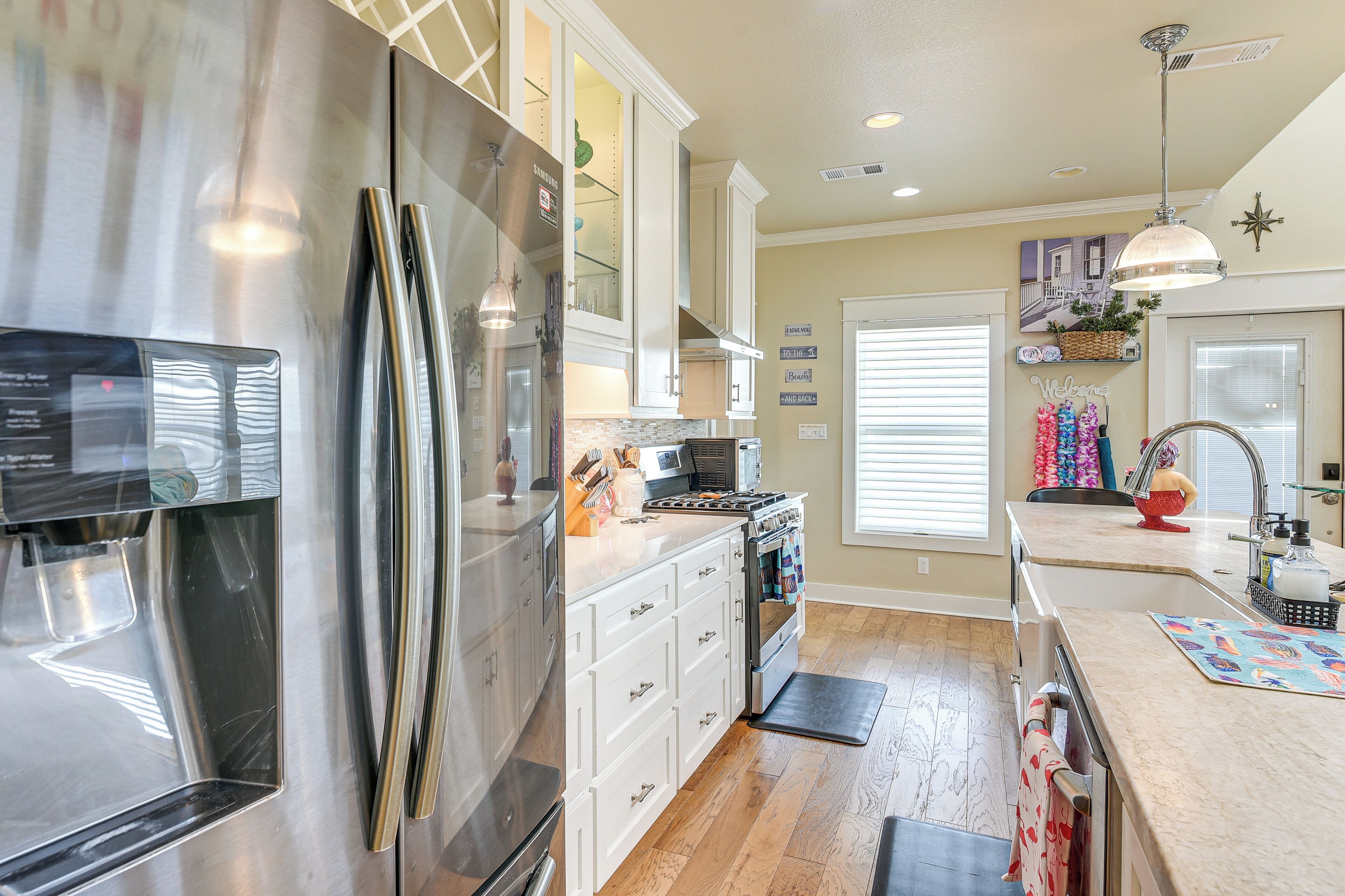 A modern kitchen with stainless steel appliances, white cabinetry, and a wooden floor.